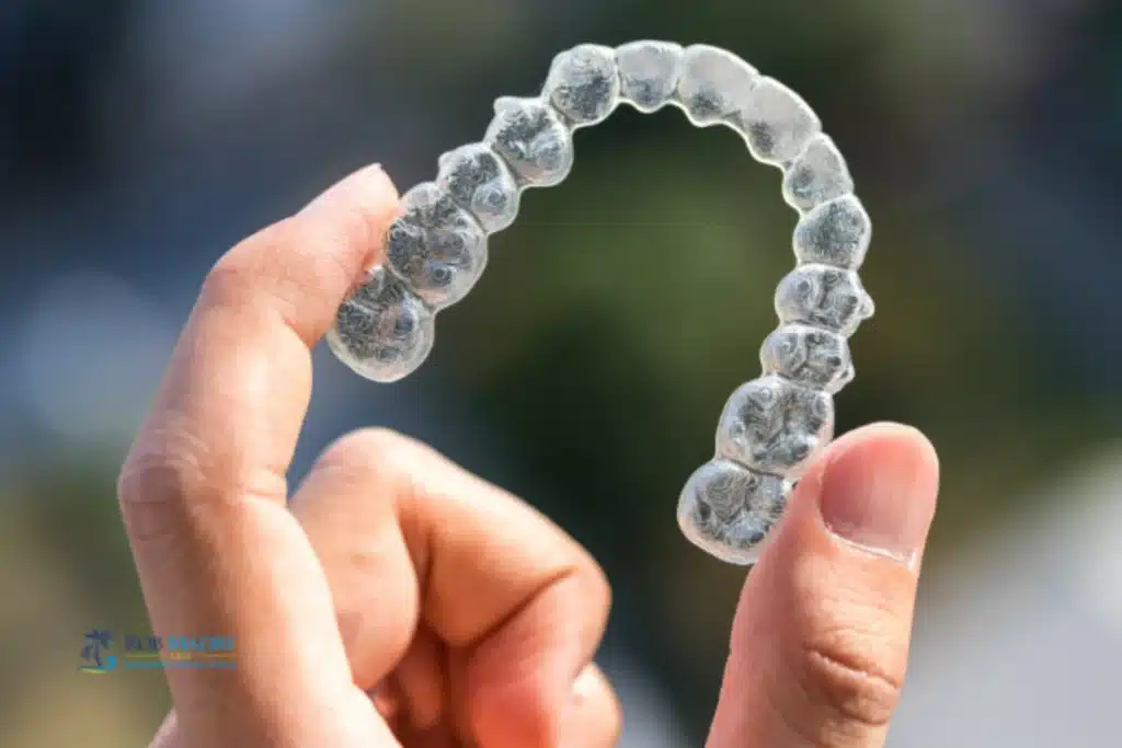 Hand holding a clear Invisalign aligner for Invisalign treatment timeline blog by Rob Madry DDS
