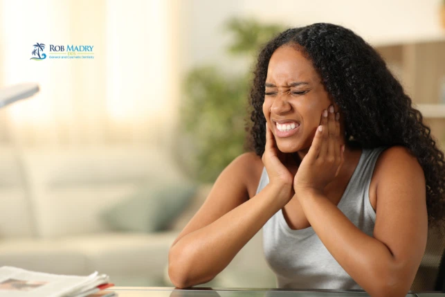Stress and TMJ jaw pain causing discomfort in a woman holding her jaw